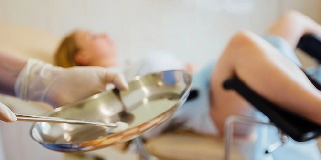 Lékař s nástrojem při gynekologickém vyšetření pacientky