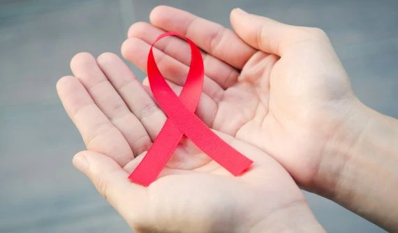 Rukou drží červený pruh symbolizující boj proti HIV.