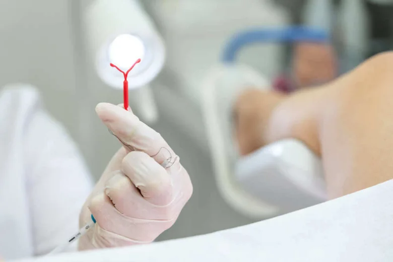 Rukou v rukavicích je drženo nitroděložní tělísko s krví.