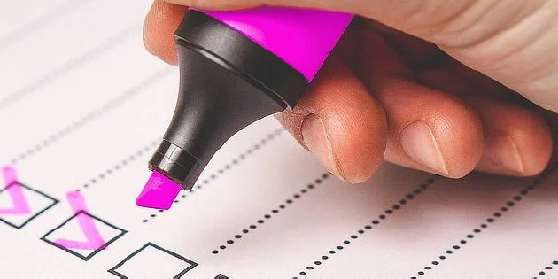 Ruka s tužkou označující kontrolní seznam na papíře.