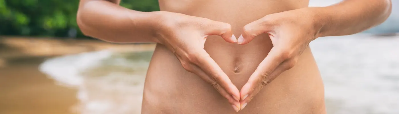 Ruce tvořící srdce na těle jako symbol zdraví.