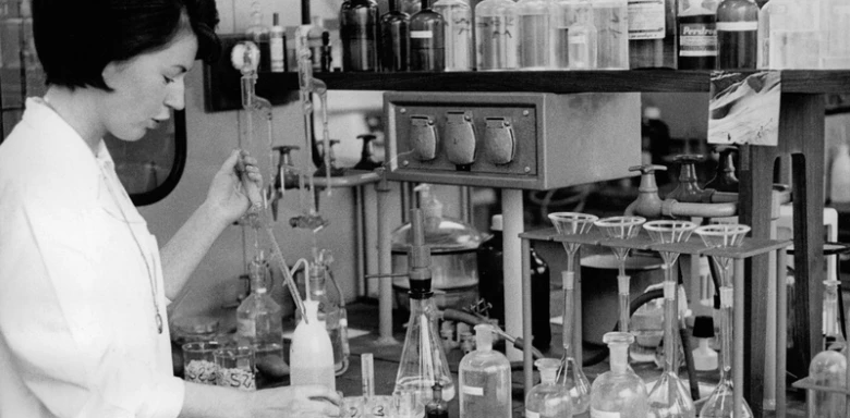 Žena v laboratoři pracuje s chemickými nádobami.