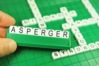 Ruka drží kostky s nápisem Asperger nad slovy syndrom a porucha.