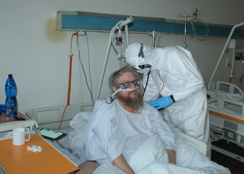 Lékař v ochranném obleku u pacienta s antivirovou terapií