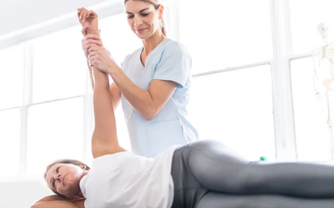 Fyzikální terapeutka protahuje paži pacienta při rehabilitaci.