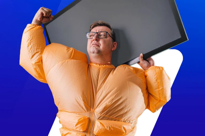 Muž v nafukovacím kostýmu drží televizi nad hlavou.