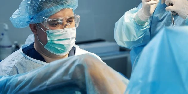 Chirurg v operační místnosti při výkonu na děloze.