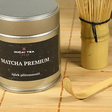 Kannička s prémiovým matchá čajem vedle bambusového šlehače.