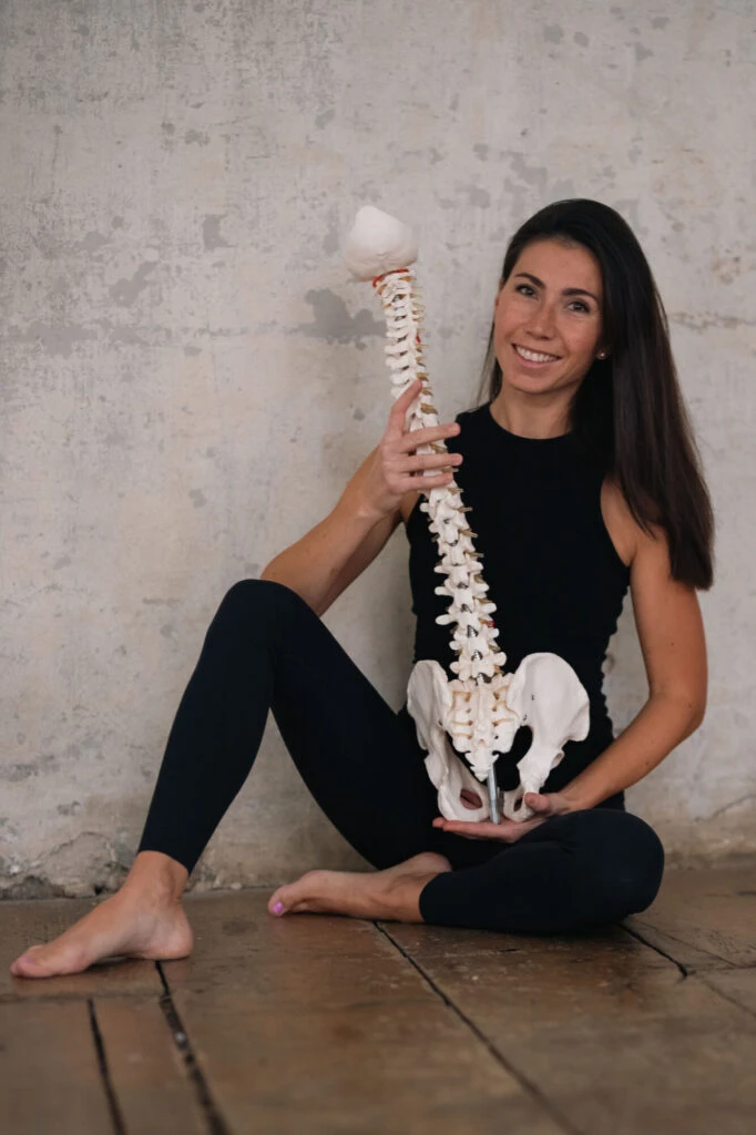 Žena drží model páteře a pánve pro vysvětlení cviků.