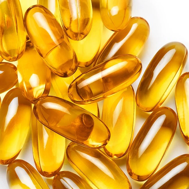 Skleněné kapsle s omega-3 mastnými kyselinami na bílém pozadí.
