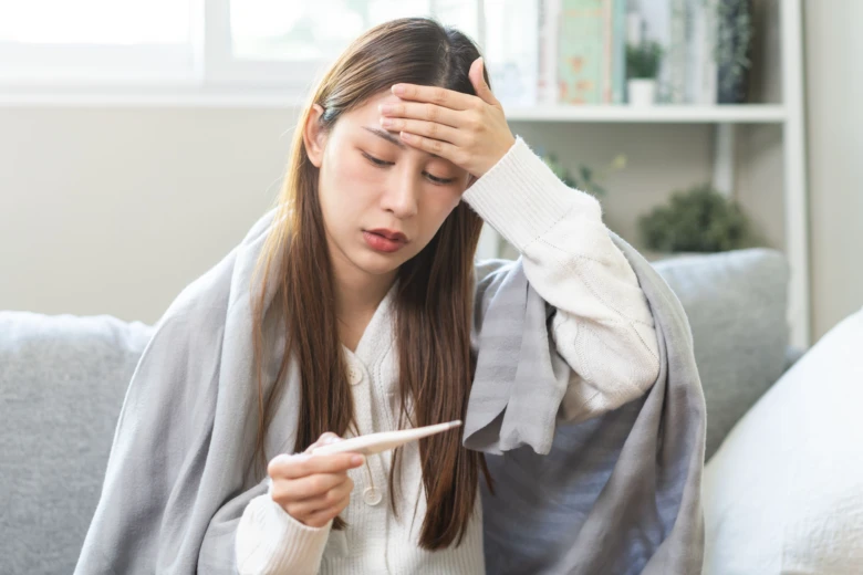 Woman with thermometer and blanket